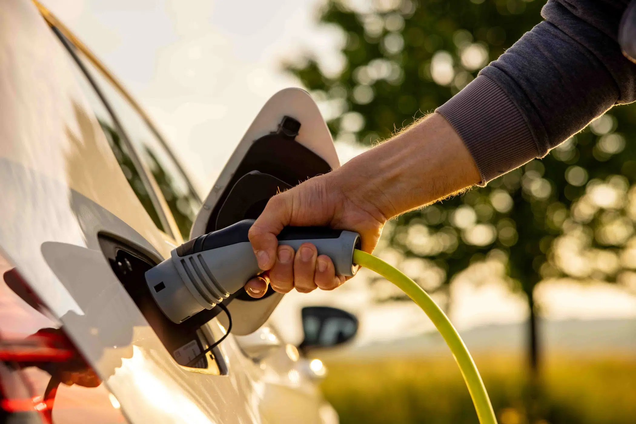 Man plugging in EV charger to electric car image