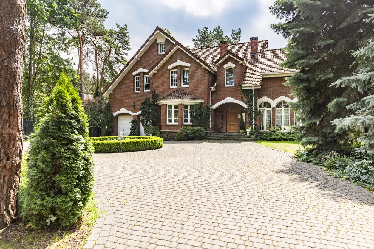 Large cobbled driveway in front of mansion house surrounded by trees image