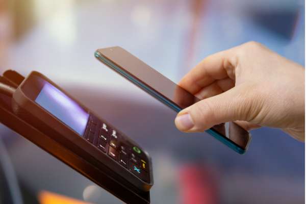 hand holding phone paying at till image