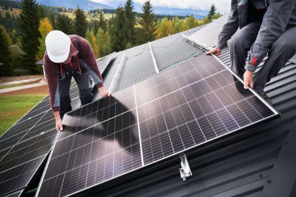 men fitting solar panels on roof image